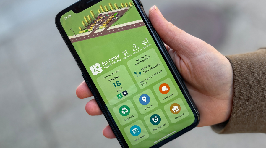 Hånd med smartphone, der viser appen Affald Favrskov
